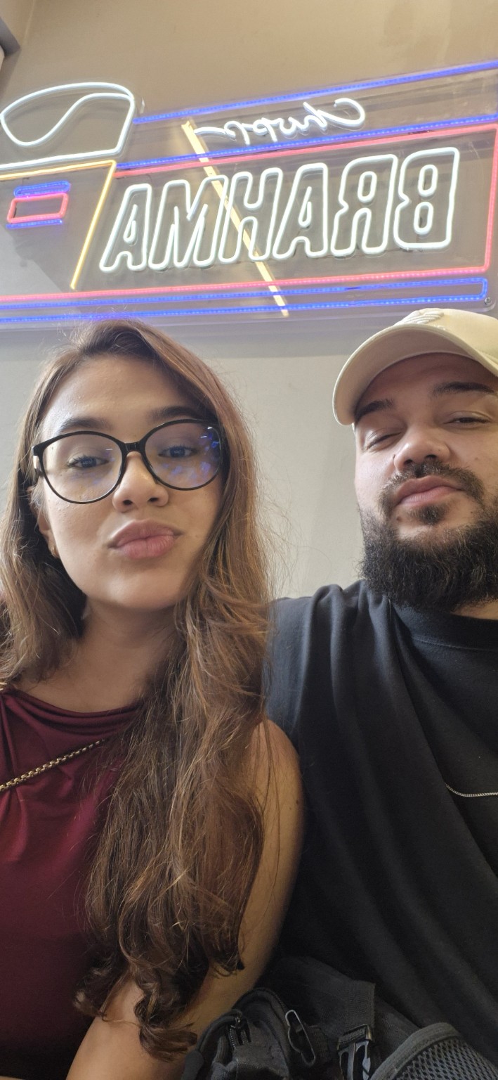Casal tirando selfie diante de um letreiro
